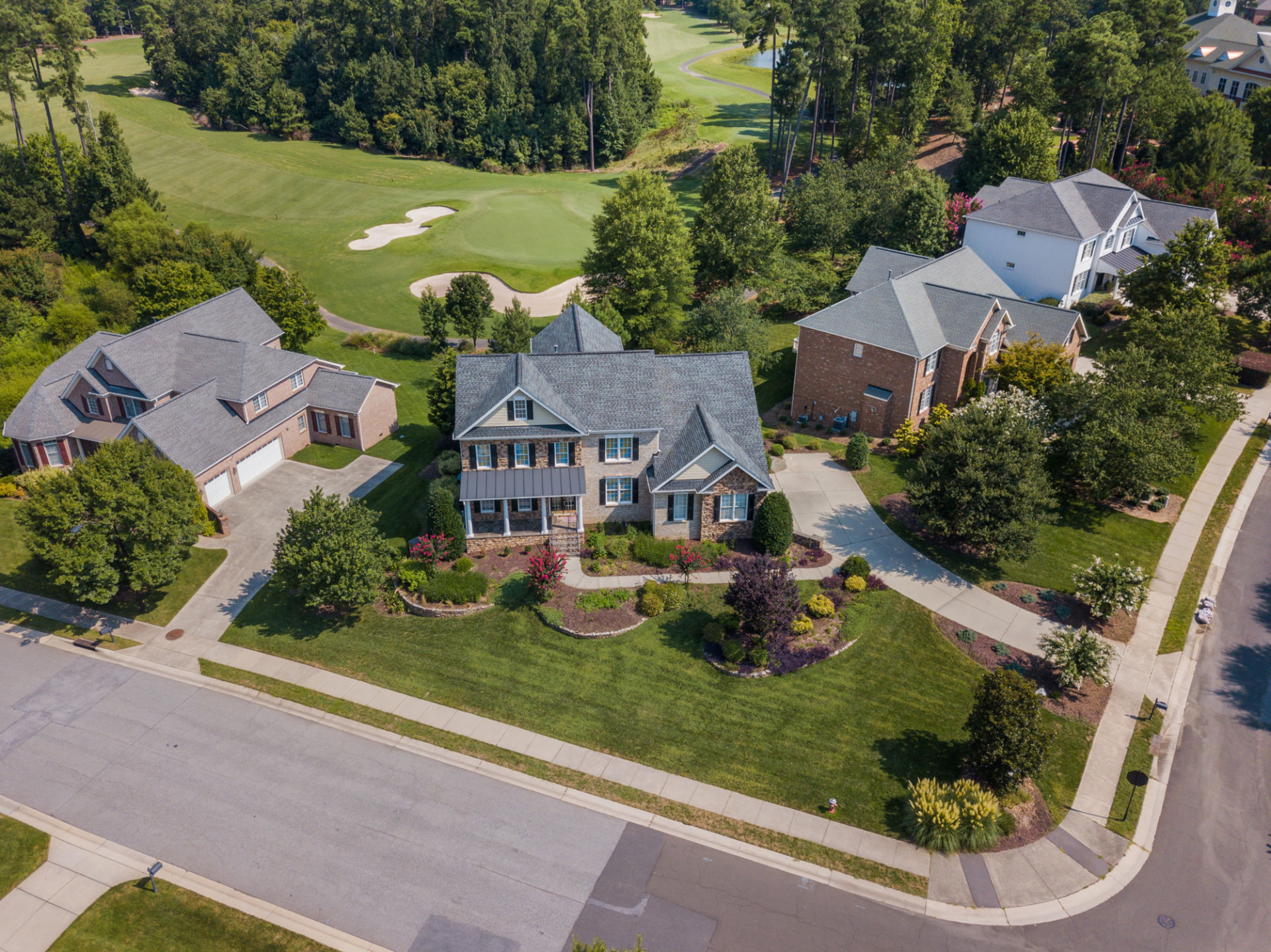 Aerial view of a single-family home community with curving streets and a golf course